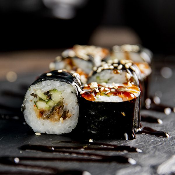 maki roll with cucumber served with sauce and sesame seeds